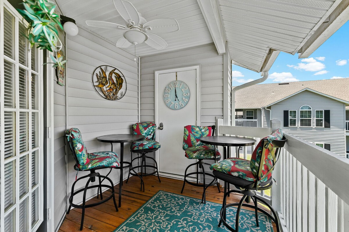Covered balcony with outdoor tables and seating.