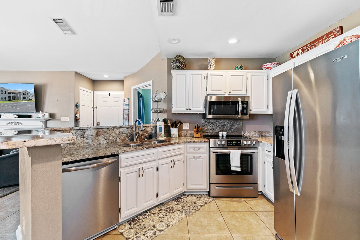 Full kitchen with white cabinets, stainless appliances, and a breakfast bar.