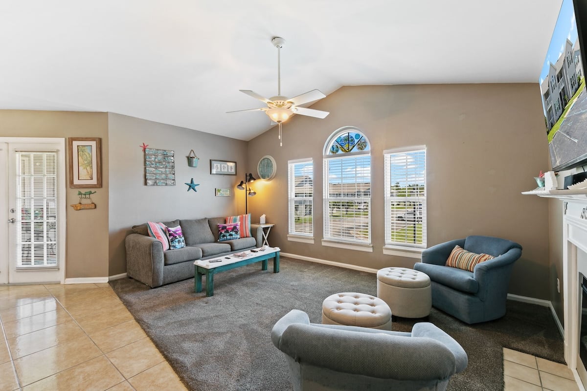 Living room at Colony Club M4, with a pullout couch, armchairs, and three windows.